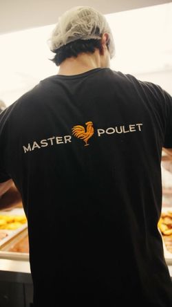 Employé portant un t-shirt "Master Poulet" dans un restaurant de poulet rôti à Vernouillet.