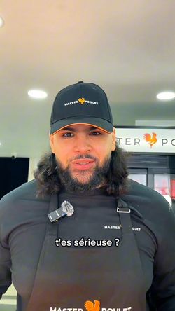 Employé portant une casquette et un tablier Master Poulet dans un restaurant rôtisserie.