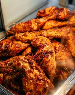 Poulets grillés bien dorés et épicés dans un restaurant rôtisserie, présentés dans un bac en métal chaud.