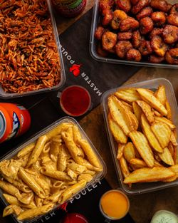 Plats à emporter composés de pâtes, frites, plantains frits et riz jollof dans des barquettes en plastique.
