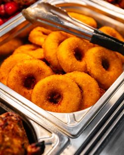 Donuts salés panés disposés dans un plat en métal avec des pinces pour servir au restaurant rôtisserie.