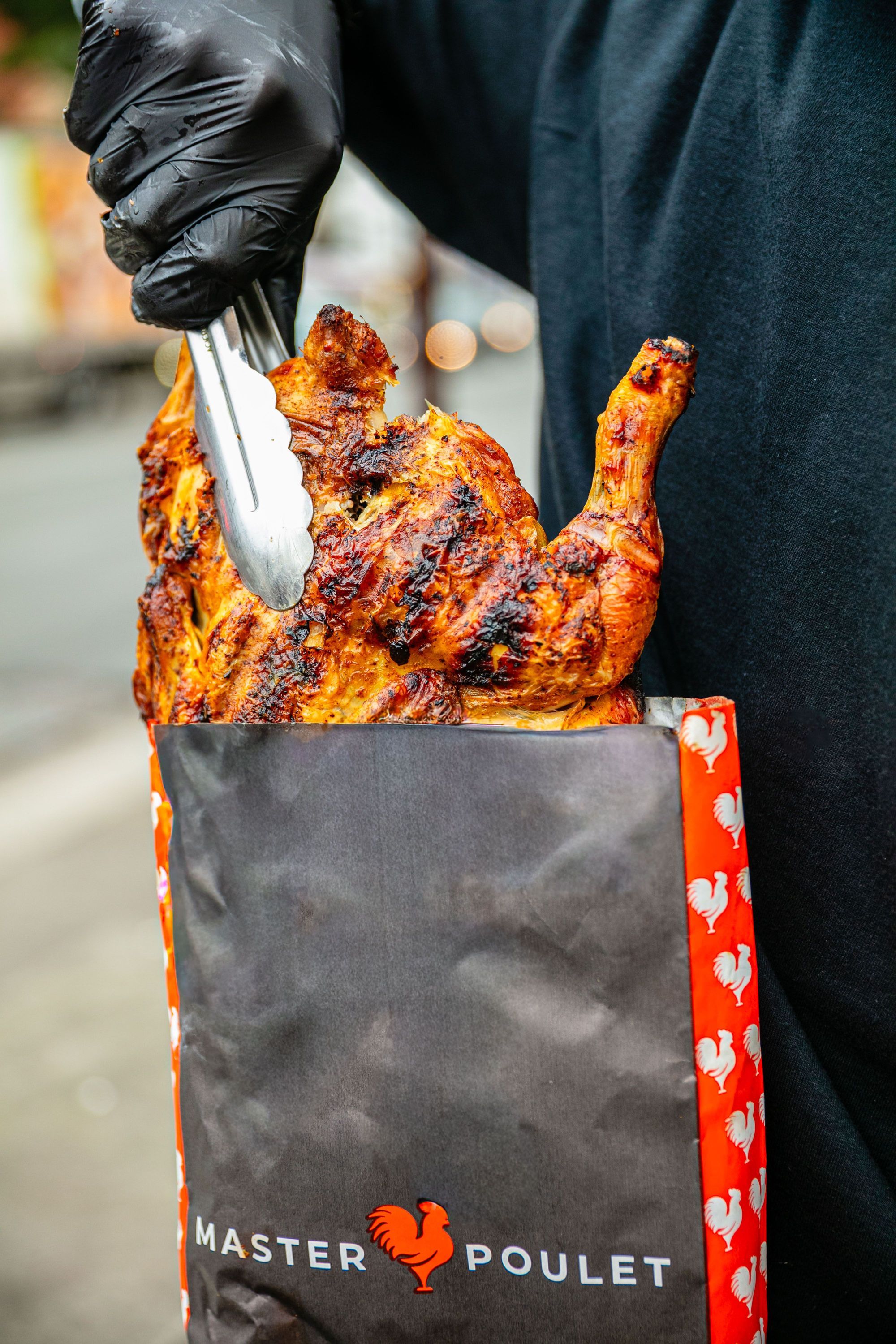 Poulet grillé appétissant sortant d'un sac aux couleurs de MASTER POULET, en attente d'être savouré.
