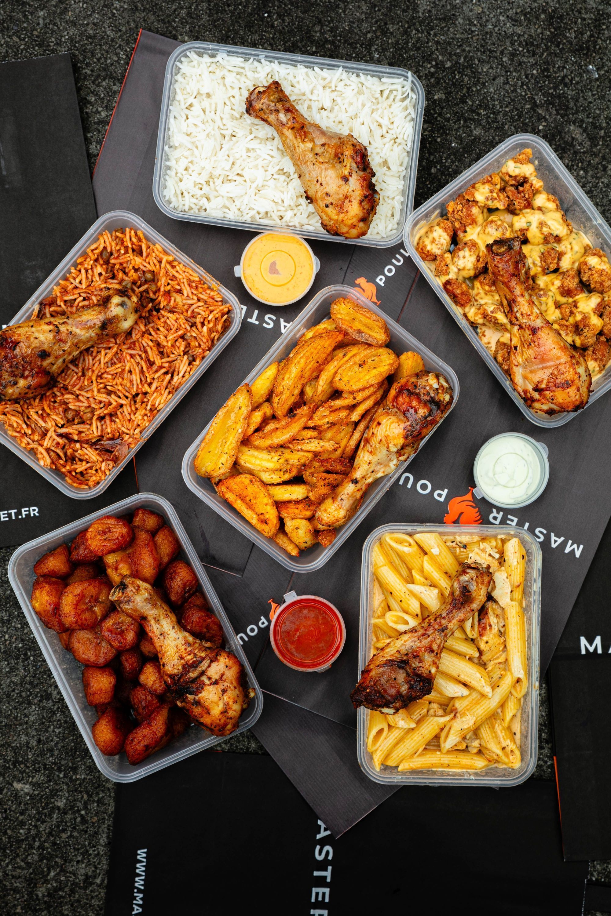 Repas à emporter avec poulet rôti servi avec riz, pâtes, plantains, légumes et sauces variées au Master Poulet.